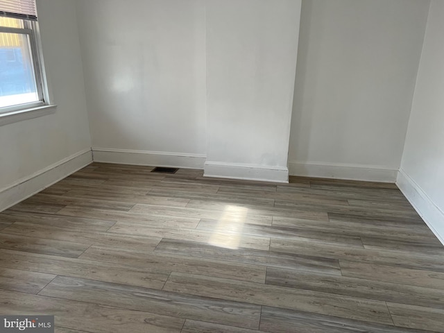 unfurnished room featuring visible vents, baseboards, and wood finished floors