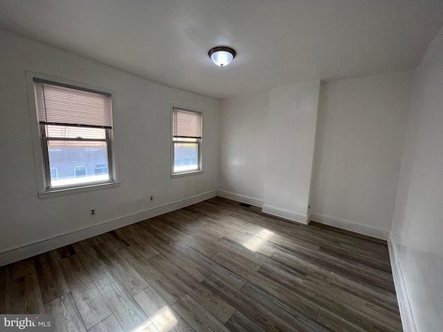 spare room with baseboards and wood finished floors