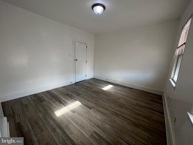 empty room featuring dark wood finished floors and baseboards