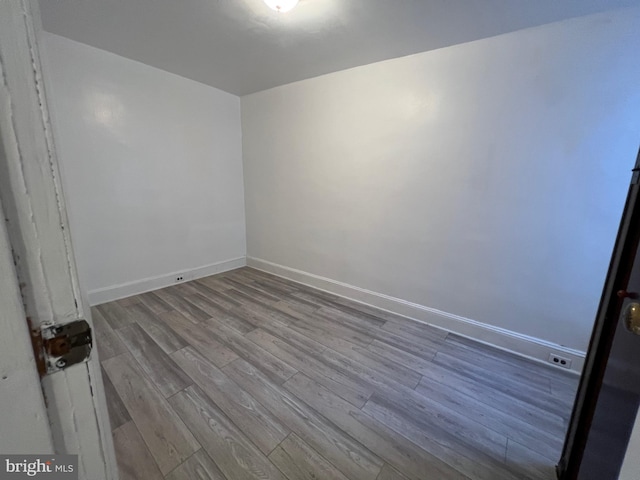 spare room with baseboards and wood finished floors