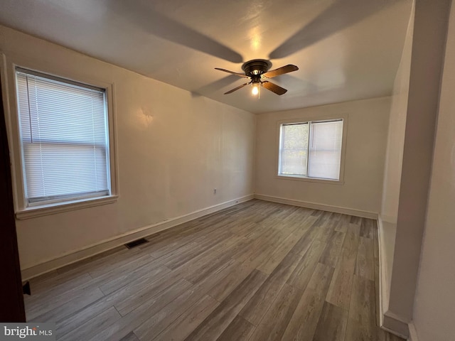 spare room with ceiling fan, wood finished floors, visible vents, and baseboards