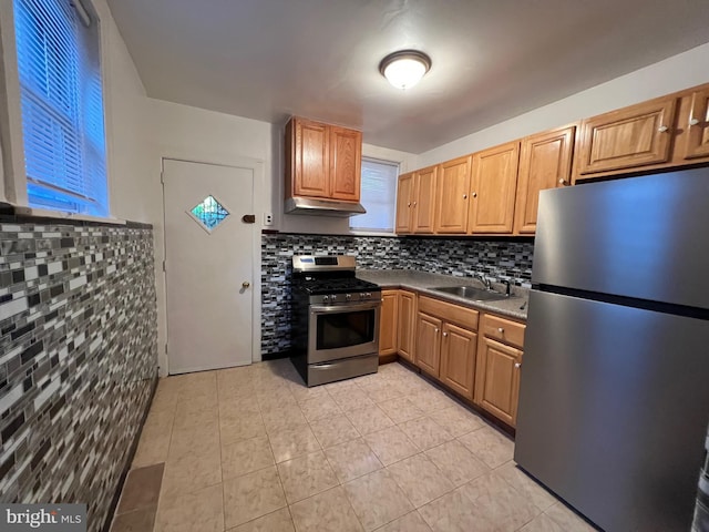 kitchen featuring light tile patterned floors, decorative backsplash, appliances with stainless steel finishes, under cabinet range hood, and a sink