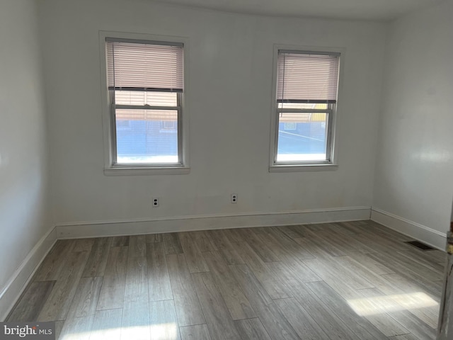 spare room featuring visible vents, baseboards, and wood finished floors