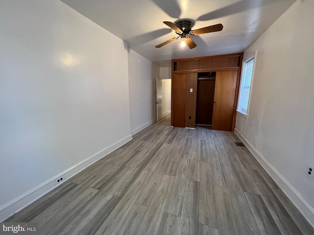 unfurnished bedroom featuring a closet, wood finished floors, a ceiling fan, and baseboards