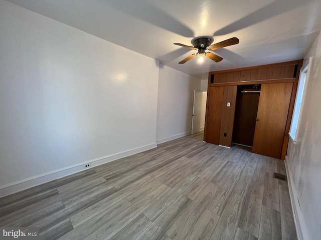 unfurnished bedroom with ceiling fan, a closet, light wood-style flooring, and baseboards