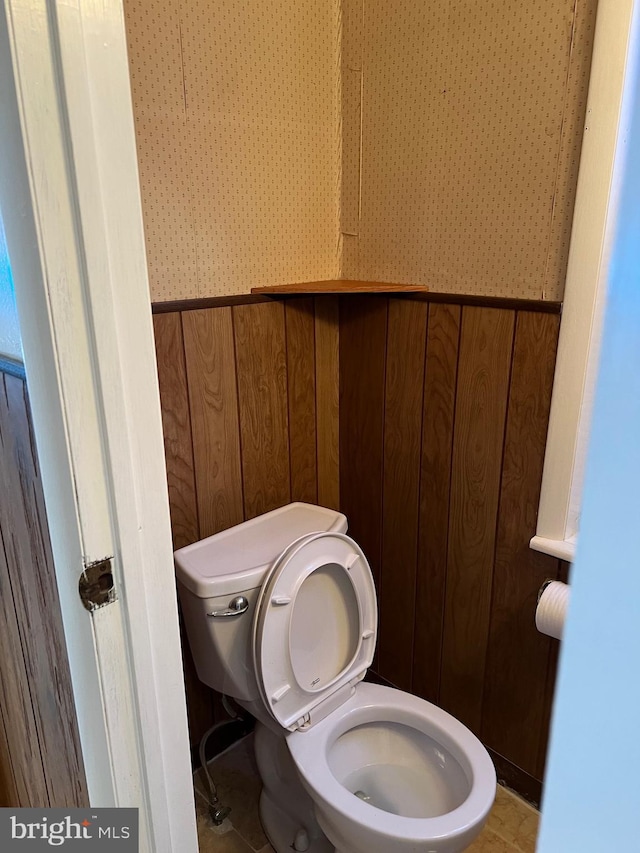 bathroom featuring toilet, a wainscoted wall, and wooden walls