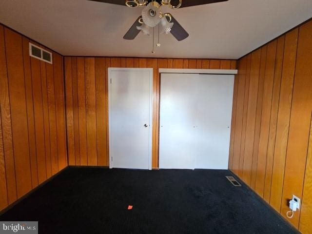 unfurnished bedroom featuring wood walls, carpet, and visible vents