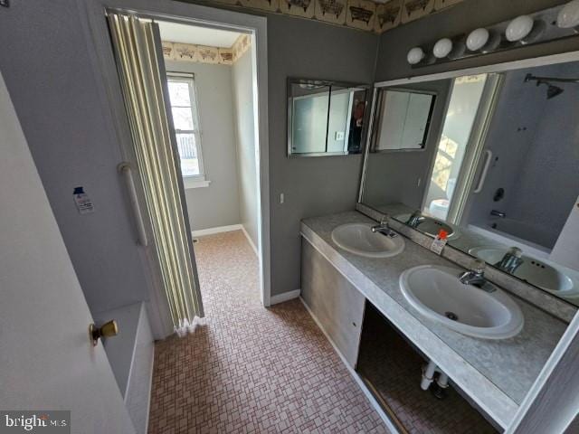 bathroom featuring a sink, a bathing tub, and baseboards