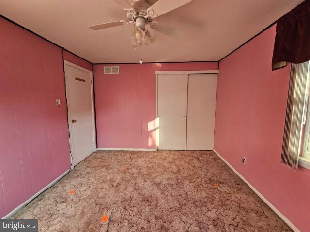 unfurnished bedroom featuring ceiling fan, carpet floors, a closet, and visible vents