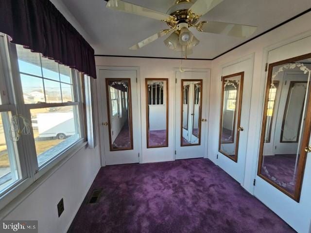 carpeted spare room featuring visible vents and a ceiling fan