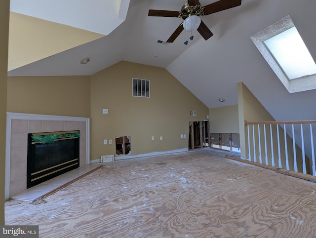 unfurnished living room with visible vents, a fireplace, a skylight, and a ceiling fan