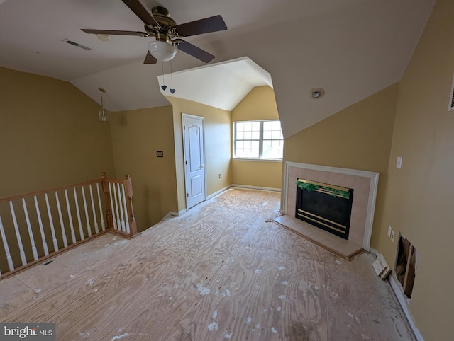 unfurnished living room with a ceiling fan, wood finished floors, visible vents, lofted ceiling, and a fireplace