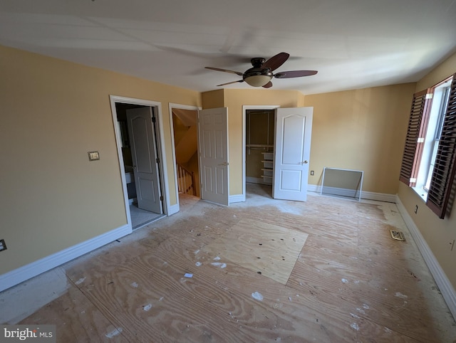 unfurnished bedroom with a closet, baseboards, a ceiling fan, and a spacious closet