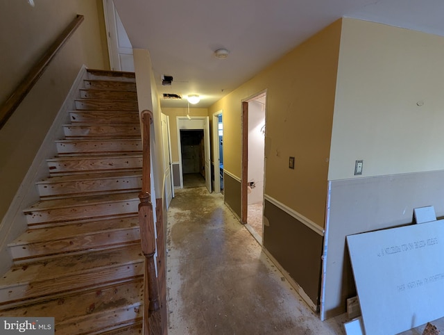 hall with stairs and unfinished concrete flooring