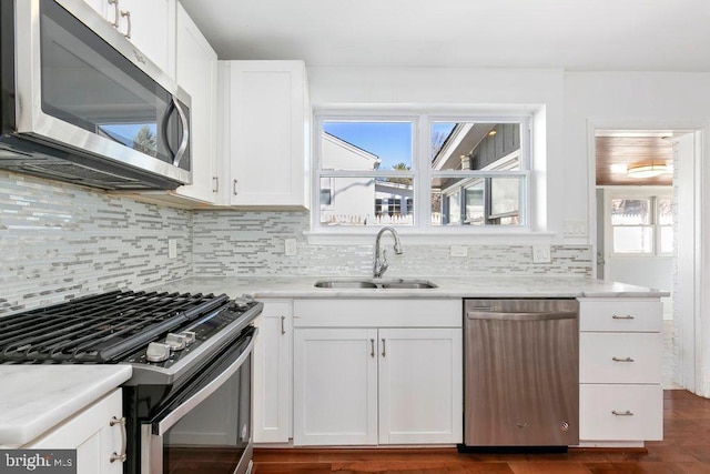 kitchen featuring a sink, backsplash, white cabinetry, and stainless steel appliances