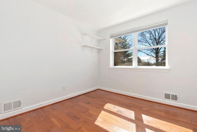 spare room with visible vents, baseboards, and hardwood / wood-style floors