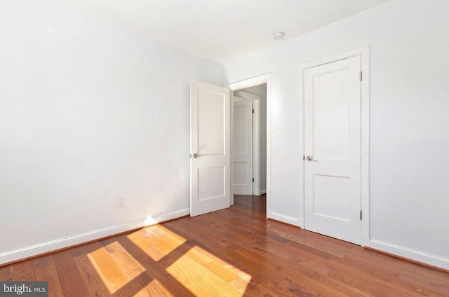 unfurnished bedroom with wood finished floors and baseboards