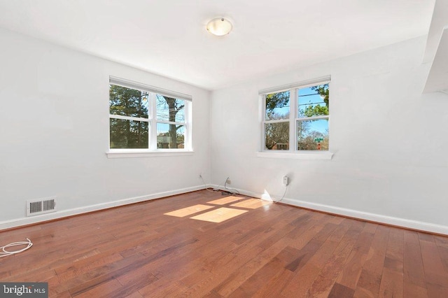 spare room featuring hardwood / wood-style floors, baseboards, and visible vents