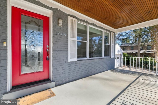 doorway to property with brick siding and a porch