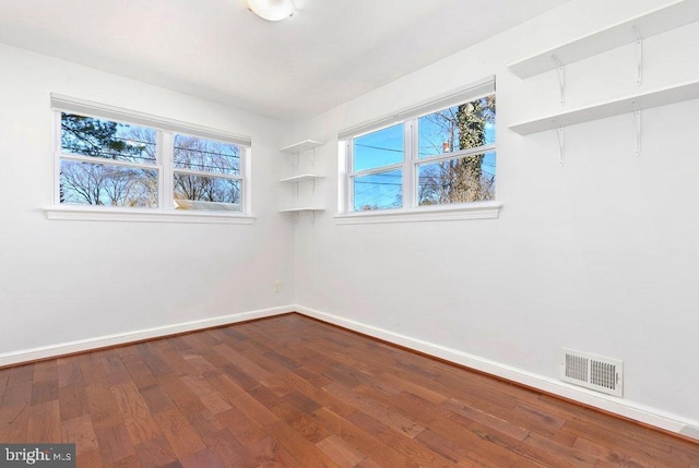 spare room with baseboards, visible vents, and dark wood-style flooring