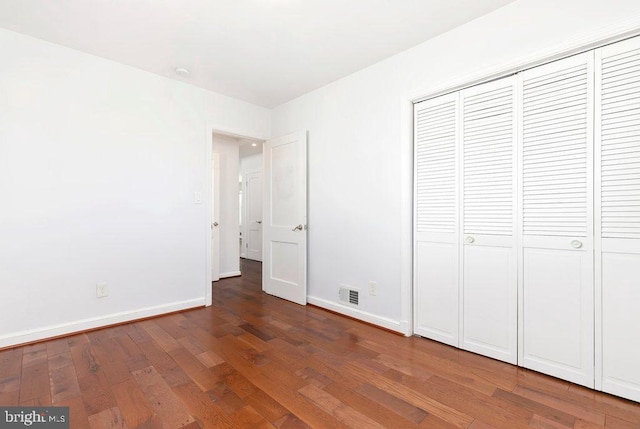 unfurnished bedroom featuring a closet, visible vents, baseboards, and hardwood / wood-style flooring