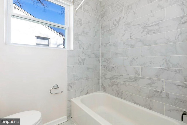 bathroom featuring toilet, shower / bath combination, and baseboards