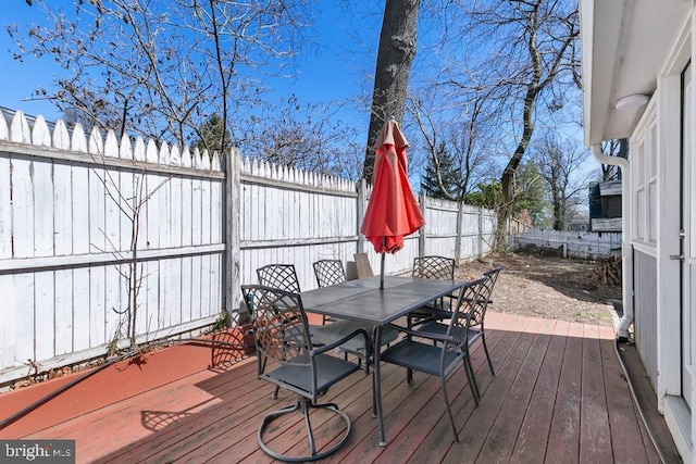 wooden terrace with outdoor dining area and a fenced backyard