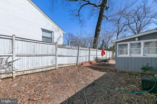 view of yard featuring a fenced backyard, outdoor dining area, and a deck