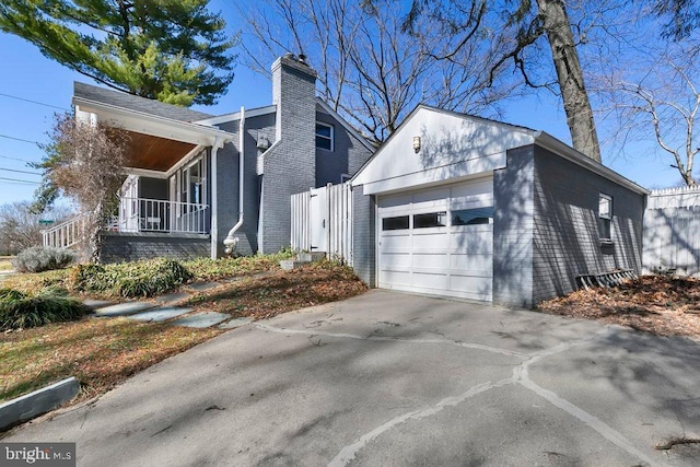 view of property exterior with an outbuilding, driveway, a porch, a chimney, and brick siding