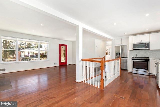 kitchen with decorative backsplash, light countertops, dark wood-style floors, and appliances with stainless steel finishes