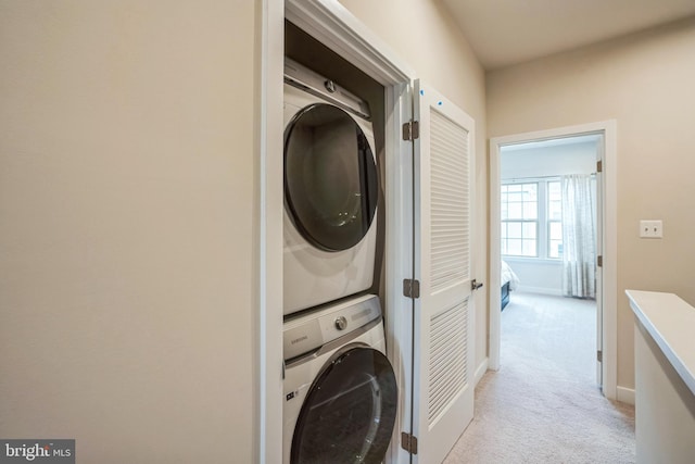 washroom with laundry area, light carpet, baseboards, and stacked washing maching and dryer