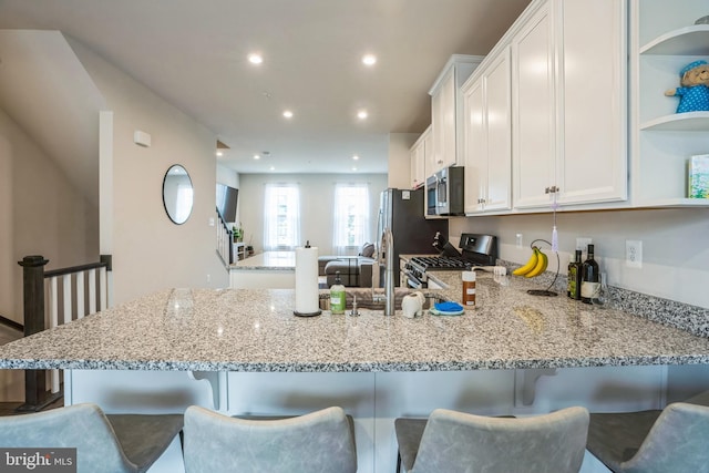 kitchen featuring open shelves, stainless steel appliances, white cabinetry, light stone countertops, and a peninsula