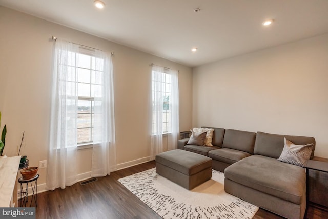 living room featuring a wealth of natural light, visible vents, and dark wood finished floors