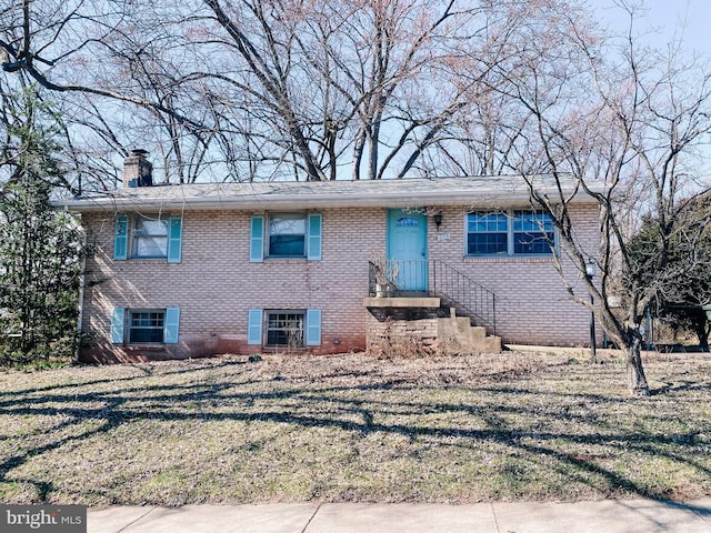 view of front of house featuring brick siding, a chimney, and a front lawn