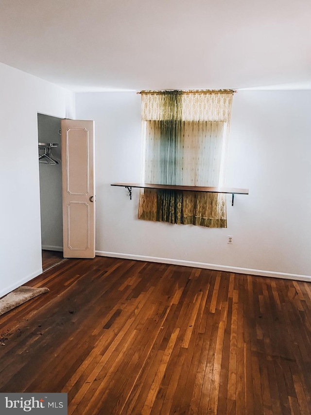 spare room featuring baseboards and hardwood / wood-style flooring