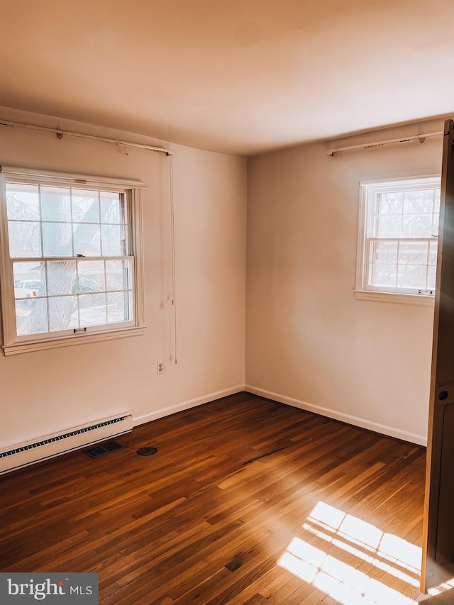 unfurnished room featuring baseboards, baseboard heating, and dark wood-type flooring