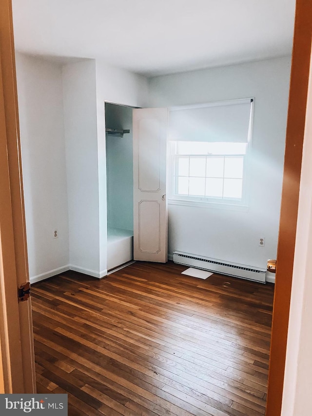 unfurnished bedroom with dark wood-style floors, a closet, and a baseboard radiator