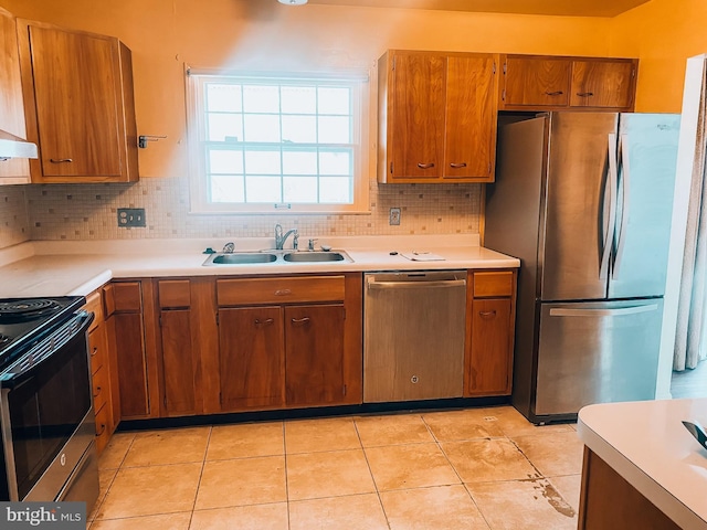 kitchen with a sink, light countertops, appliances with stainless steel finishes, decorative backsplash, and brown cabinetry