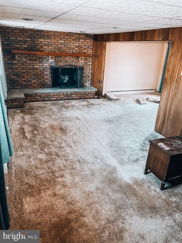 unfurnished living room with carpet, a fireplace, and wooden walls