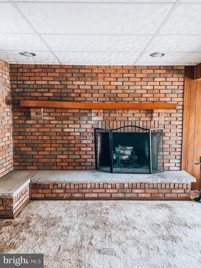 room details featuring carpet, a fireplace, and a paneled ceiling