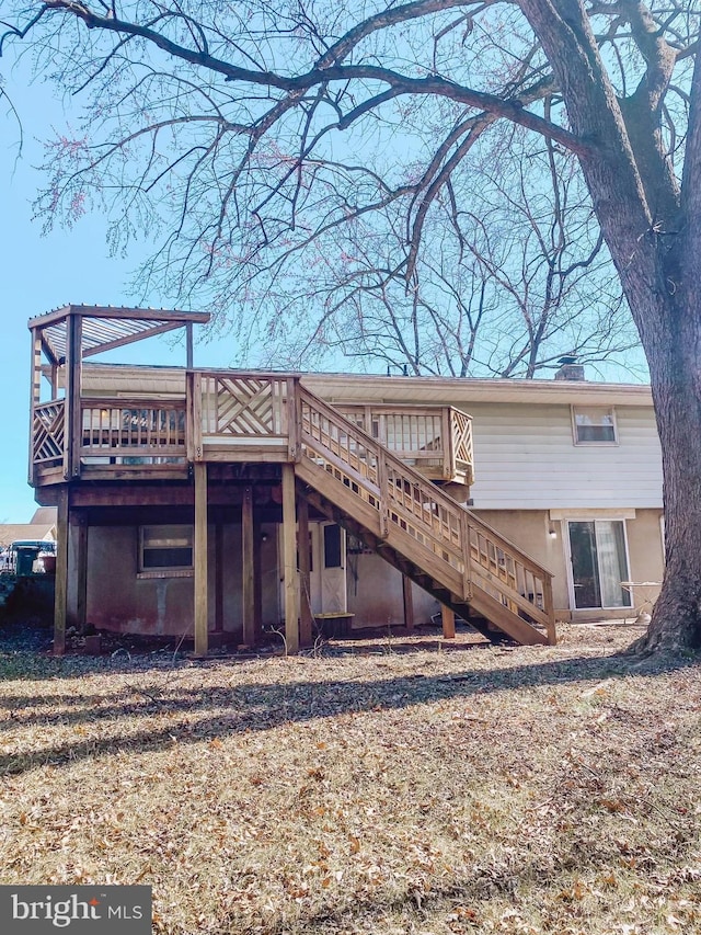 back of property with stairway, a chimney, and a wooden deck