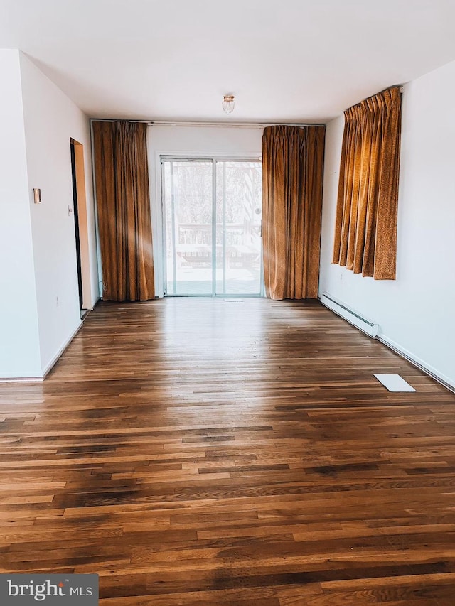 unfurnished room with a baseboard radiator and wood finished floors