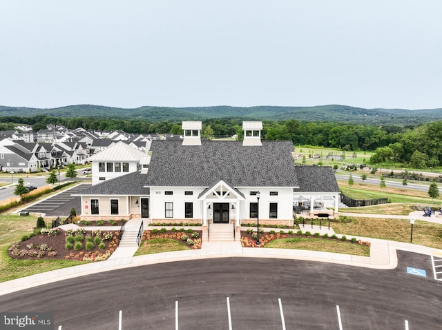 view of front facade with uncovered parking, a residential view, and roof with shingles