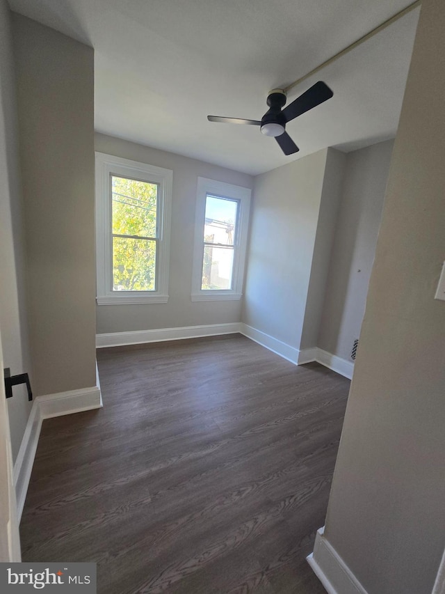 unfurnished room with dark wood-style floors, ceiling fan, and baseboards