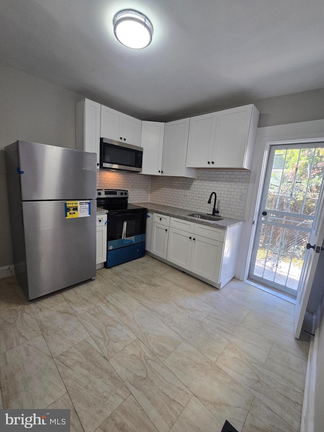 kitchen with stainless steel appliances, white cabinetry, a sink, and tasteful backsplash