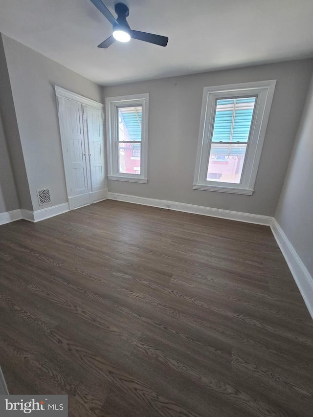 unfurnished bedroom featuring visible vents, dark wood finished floors, baseboards, and ceiling fan