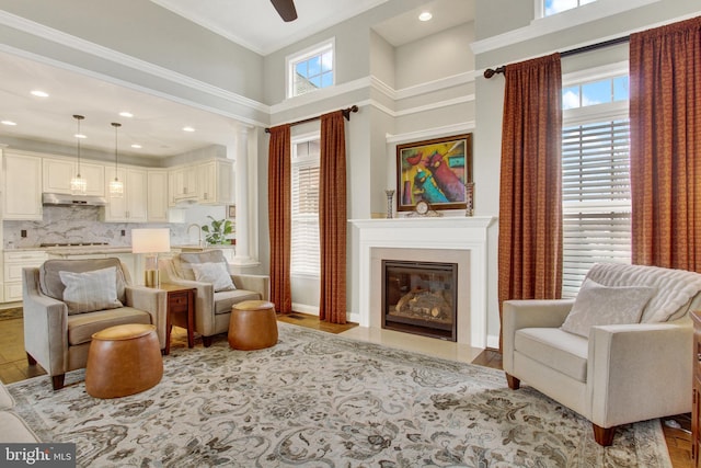 living area featuring recessed lighting, a fireplace with flush hearth, wood finished floors, a towering ceiling, and a ceiling fan