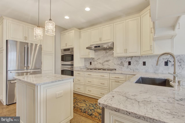 kitchen with tasteful backsplash, light stone countertops, stainless steel appliances, under cabinet range hood, and a sink