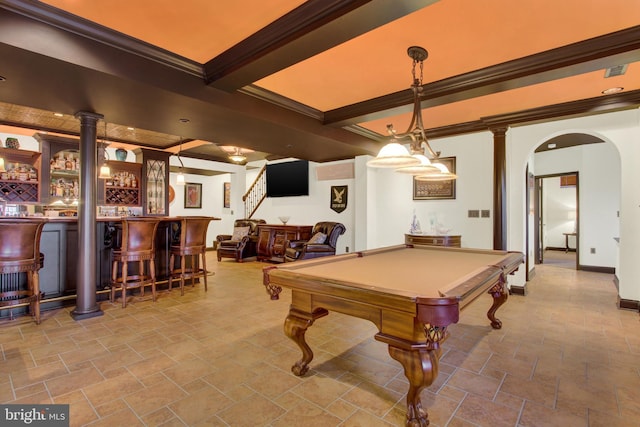 recreation room featuring arched walkways, crown molding, stone finish flooring, a bar, and beamed ceiling