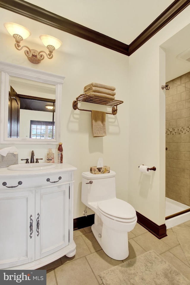 full bathroom featuring toilet, ornamental molding, vanity, tiled shower, and baseboards